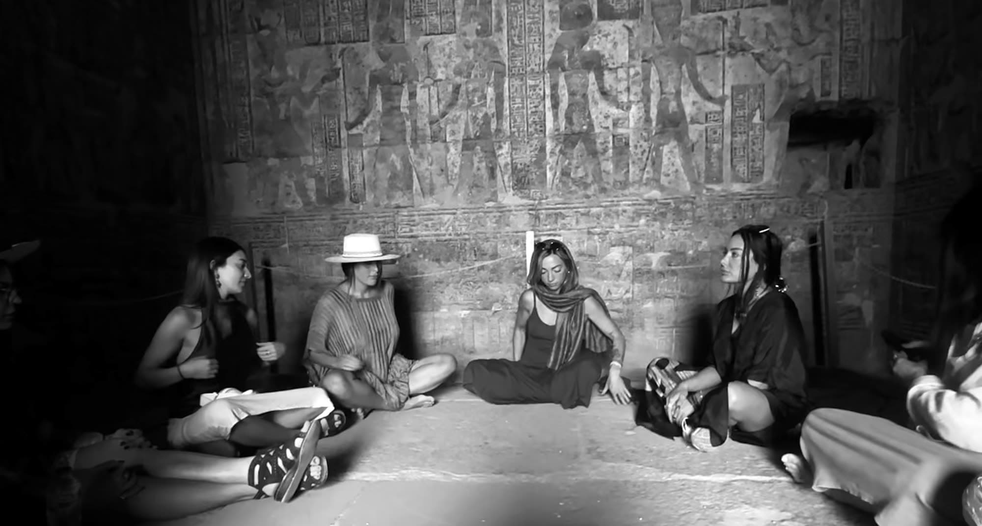 Women in ceremony on the stone floor of a carved temple chamber in Egypt